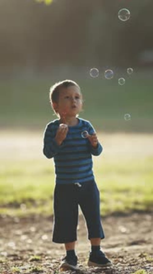 Child Blowing Bubbles Wand Outdoors in the Park