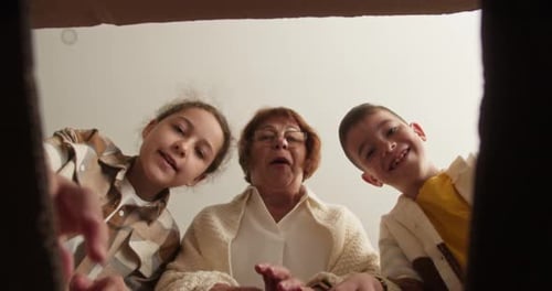Grandmother and Grandchildren Excitedly Opening a Box