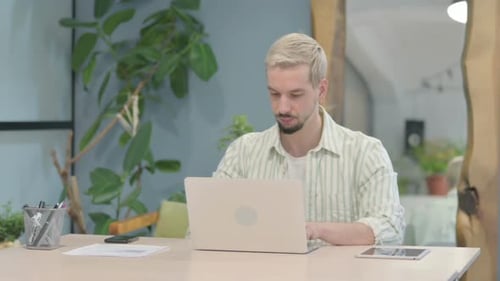 Young Adult Working on Laptop in Modern Home Office