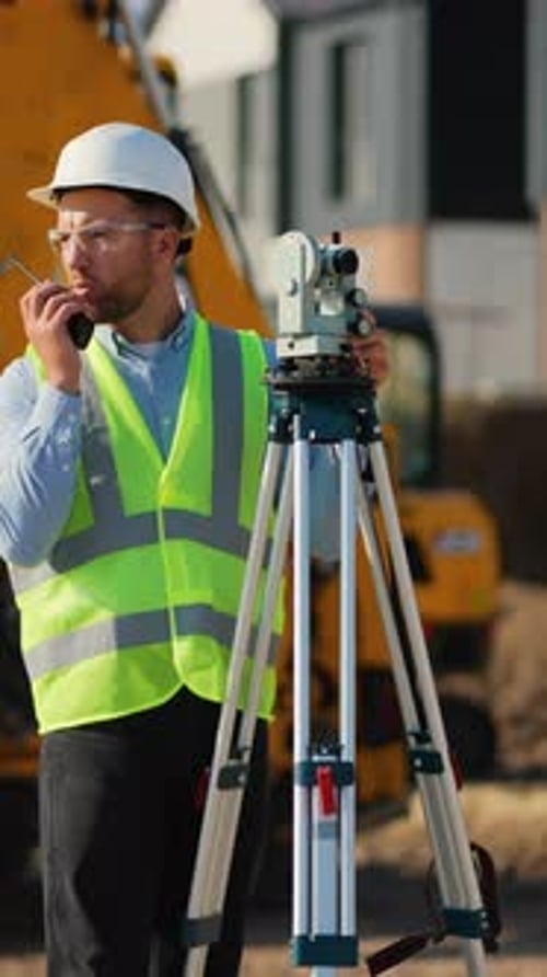Surveyor Using Theodolite and Radio on Construction Site