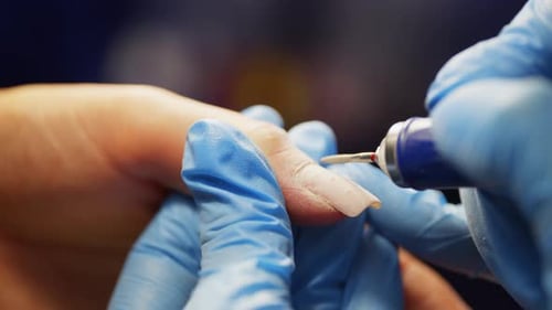 Manicurist Filing Nails with Electric File in Salon