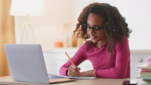 Focused girl studying and writing in notebook
