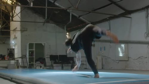 Junger männlicher Turner macht Wagenrad und Salto im Fitnessstudio