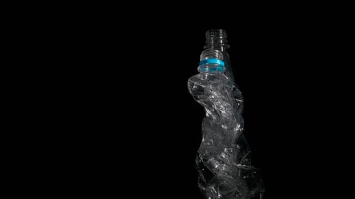 Crushed Plastic Bottles on Black Reflective Surface