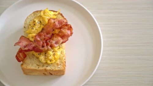 Toast Topped With Eggs And Bacon On Plate