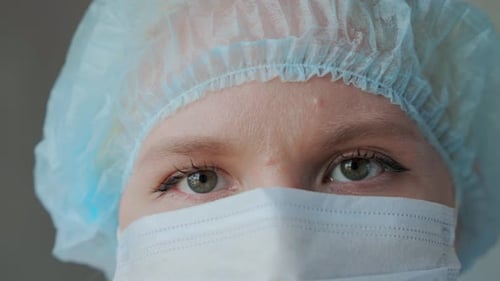 le visage d'une jeune femme médecin portant un masque médical de protection et une cape