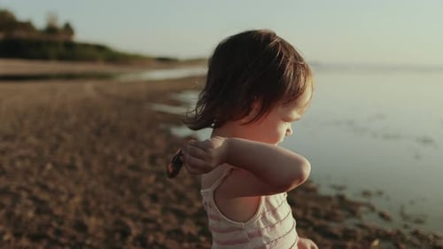 A Young Child Happily Engaged in Play By the Water During a Gorgeous Sunset Setting