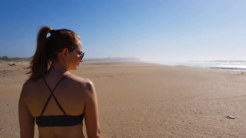 Following a woman walking on the beach enjoying the sun