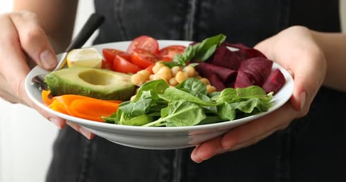 Hands hold colorful and healthy vegan salad bowl