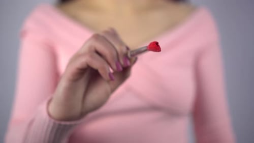 Woman Draws Red X with Lipstick Brush