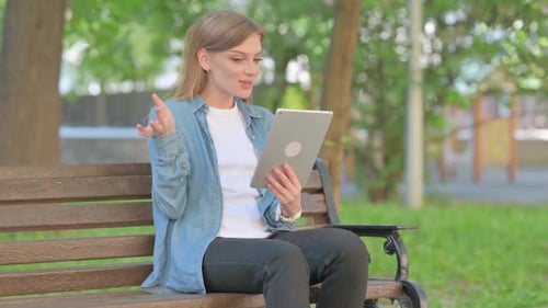 Outdoor Sitting Young Woman Doing Video Chat on Tablet