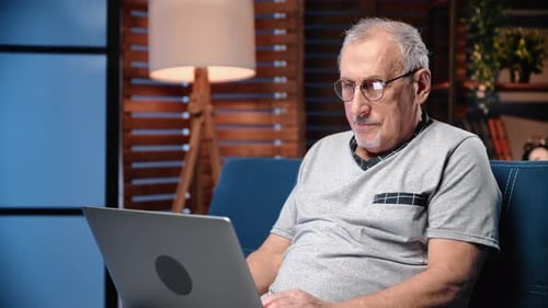 Senior Man Using Laptop Computer on Couch