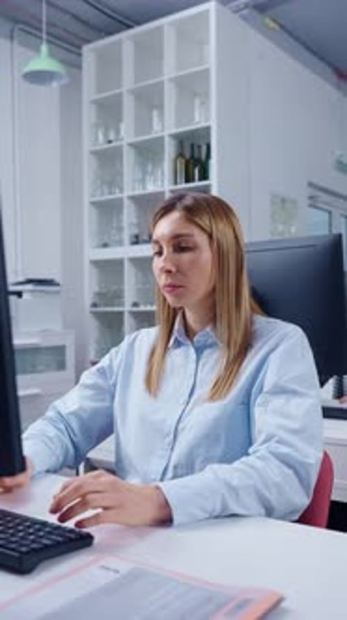 Focused Office Worker Typing on Computer at Modern Workstation Concentrating on Online Tasks While