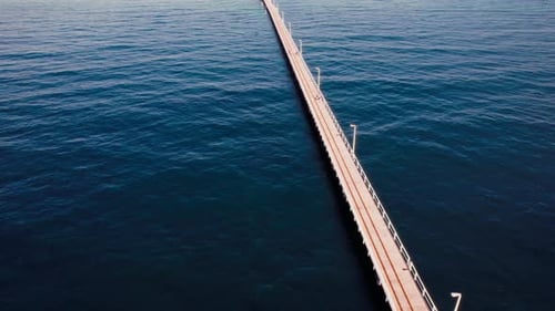 Long wooden pier stretches into calm blue waters