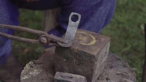 Blacksmith Shaping Metal with Tongs on Anvil