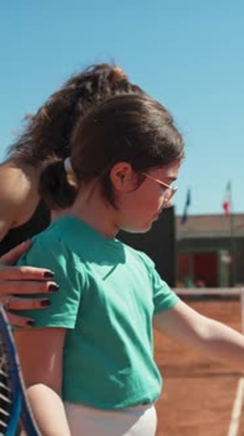 Female Instructor Teaches Little Girl How To Move Tennis Racket In The Field