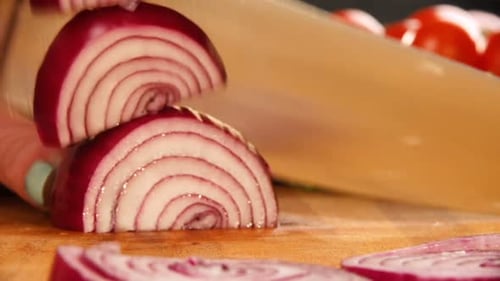 Woman slicing red onion on wooden cutting board