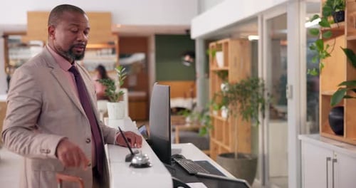 Man Standing at Reception Desk in a Hotel Lobby