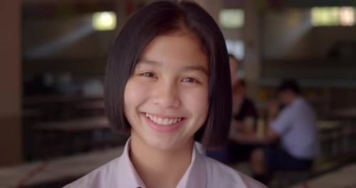 Slow motion scene of a young Asian teenage high school student girl is smiling happily.