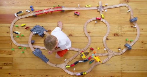 Child Playing with Wooden Train Set on Floor