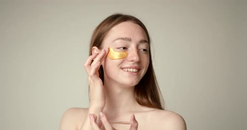 Woman Applies Golden Eye Mask for Beauty Treatment