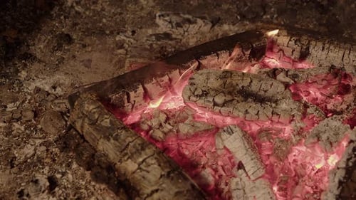 Glowing red hot embers remain as camp fire burns logs down to ash