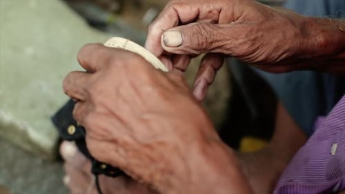 A cobbler repairing slippers of pilgrims by the roadside in the morning stock footage collection 3