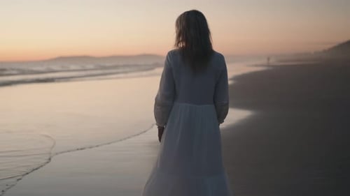 Woman Standing On Beach At Sunset