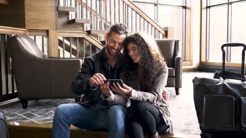 Ralenti d'un couple avec des valises regardant le téléphone dans le hall de l'hôtel