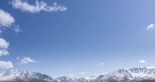 Timelapse du mouvement du soleil sur un ciel cristallin avec des nuages au-dessus de la neige, sommet de la montagne, herbe jaune à