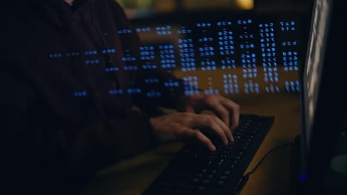 Focused Hacker Typing Code on Computer at Night