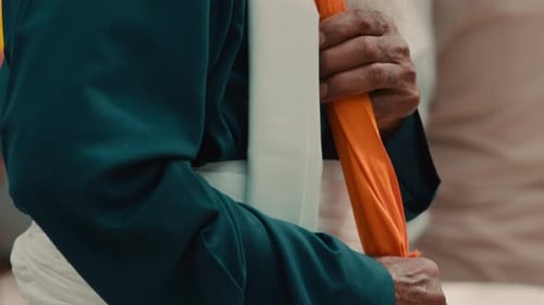 Close-up of a Senior Man's Hands Holding an Orange Flag Pole