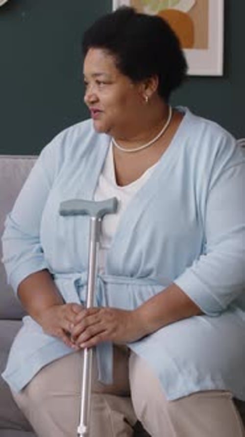 Senior Woman Sitting with Cane Indoors