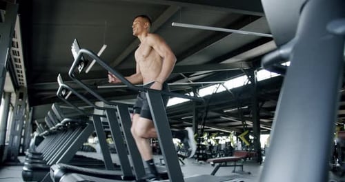 Athletic man exercising at gym and running on treadmill