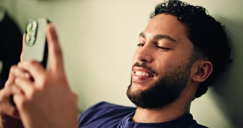 Smiling Young Man Using Mobile Phone Indoors