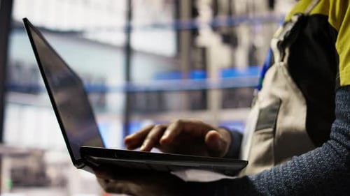 Nahaufnahme eines intelligenten Fabrikarbeiters, der einen Laptop zum Testen automatisierter Systeme verwendet