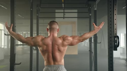 Medium Shot Back View of Bodybuilder Showing His Biceps and Triceps Back