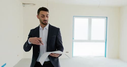 Happy Successful Middle Eatern Real Estate Agent Holding Building Plan in Hands Talking About a New