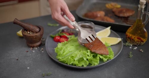 Tongs Placing Meat on Plate With Lettuce