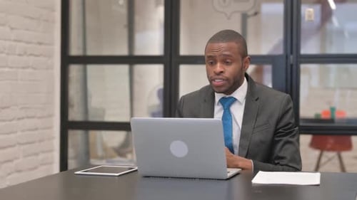 Man in Suit Gives Virtual Presentation at Desk