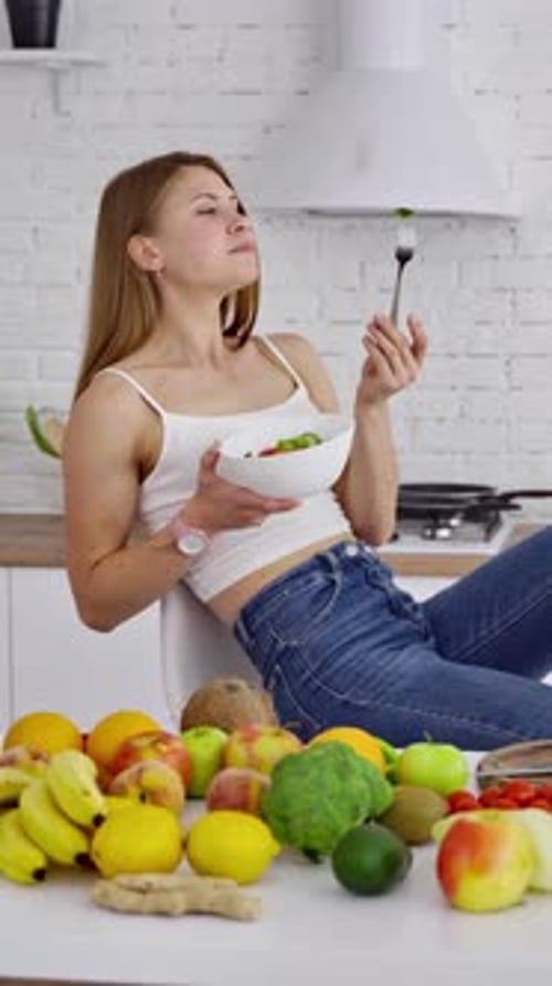 Young Woman Enjoys Fresh Salad at Kitchen Counter