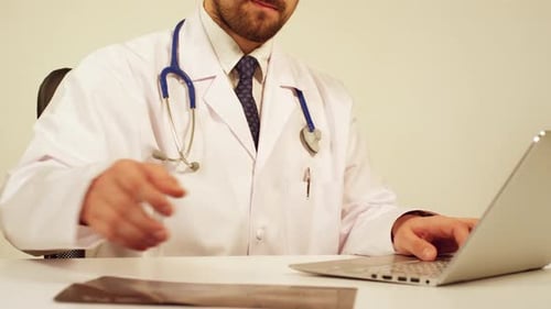 Doctor Analyzes X-Ray While Using Laptop