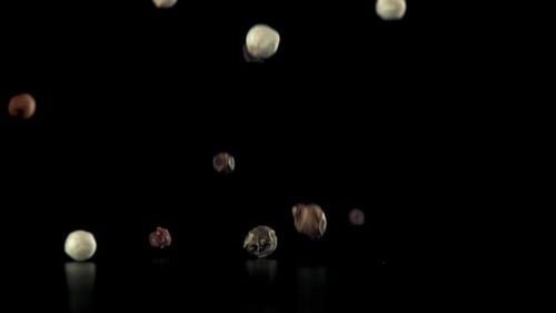 Falling Multicolored Peppercorns in Slow Motion on Black