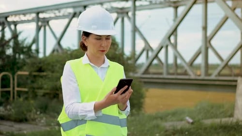 Woman Engineer Using Smartphone Near Train Bridge