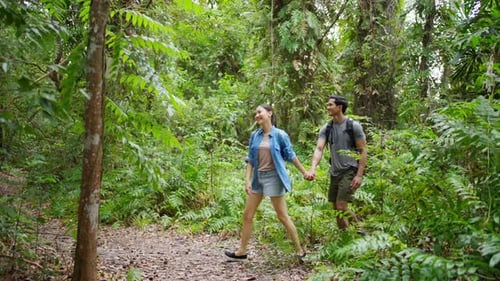 4K Young Asian couple hiking together in tropical forest.