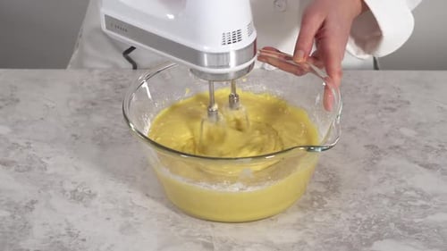 Nahaufnahme, wie Zutaten in einer Glasrührschüssel gemischt werden, um den Funfettti Bundt-Kuchen zu backen