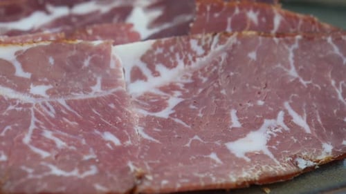 Una vista de cerca de la carne curada jaspeada bellamente dispuesta en un plato