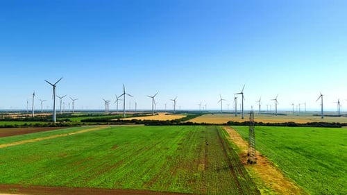Multiple powerful wind mills rotate in the wind in the countryside.