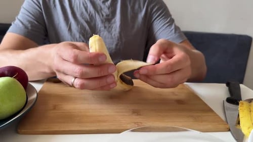 Man Prepares and Slices Banana on Cutting Board