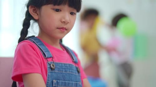 Young Girl Drawing With Classmates in School